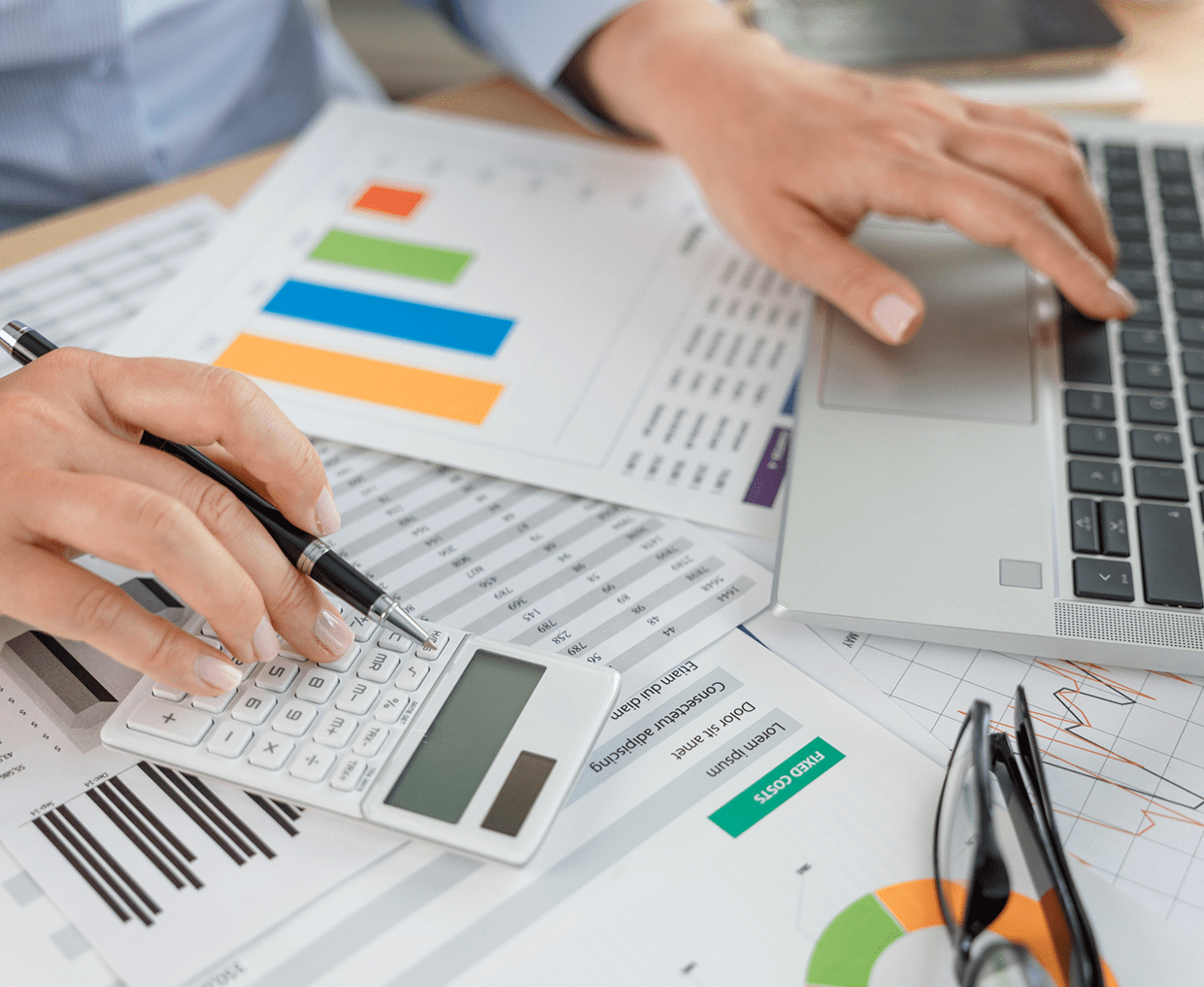 Hands typing on laptop with graphs