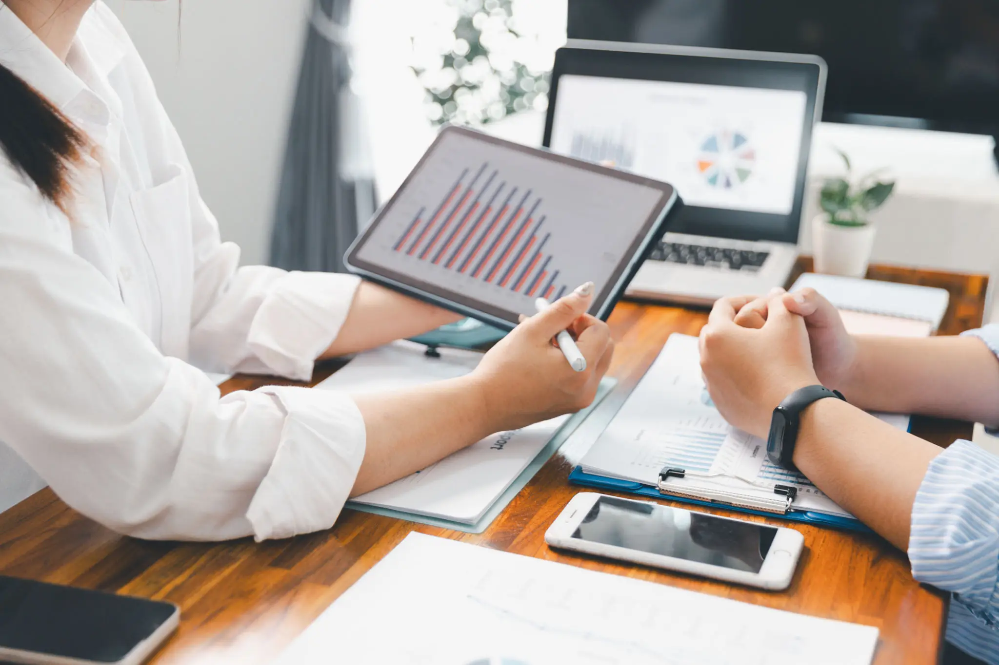 Two professionals discussing a digital sales report on a tablet.