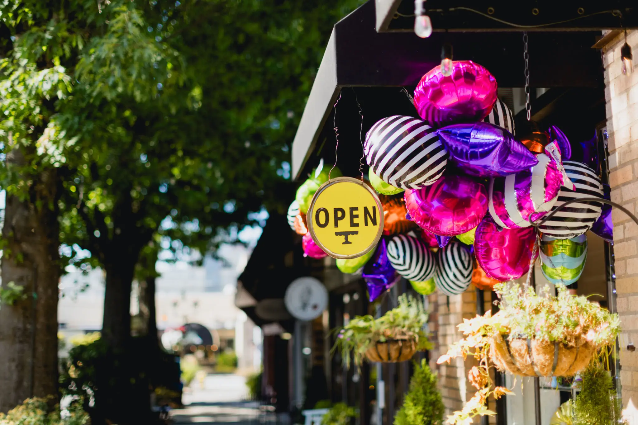 Colorful hanging decorations and an open sign outside a shop.