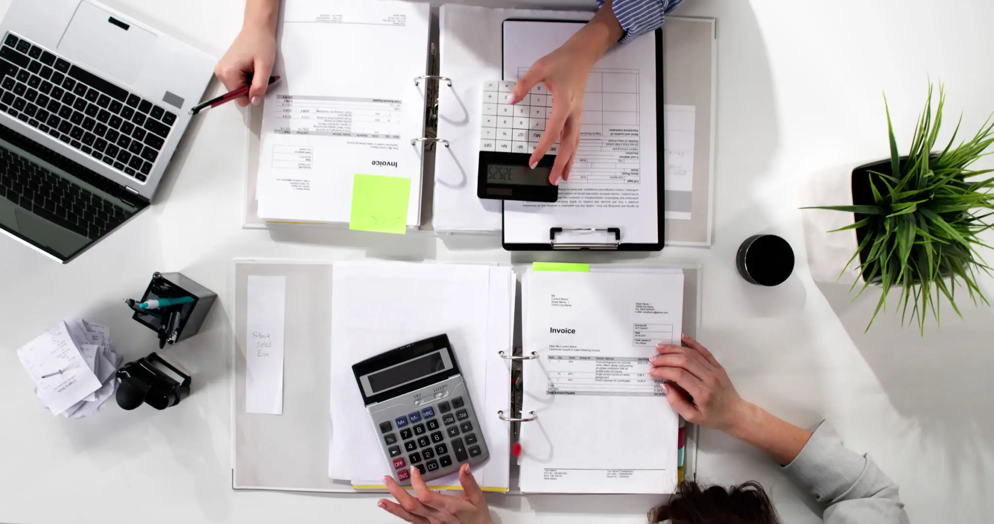 People working on financial documents with calculators and laptops.